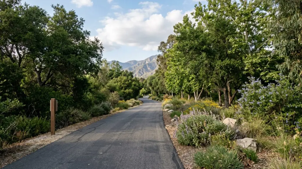 A segment of the paved Pacific Electric Trail stretching into the distance, flanked by mature trees and desert landscaping, with no people visible.